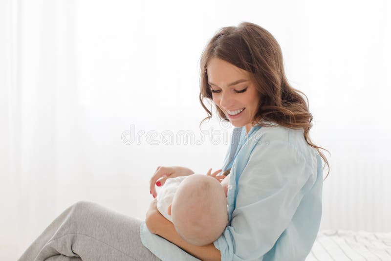 Cheerful woman with baby breast feeding