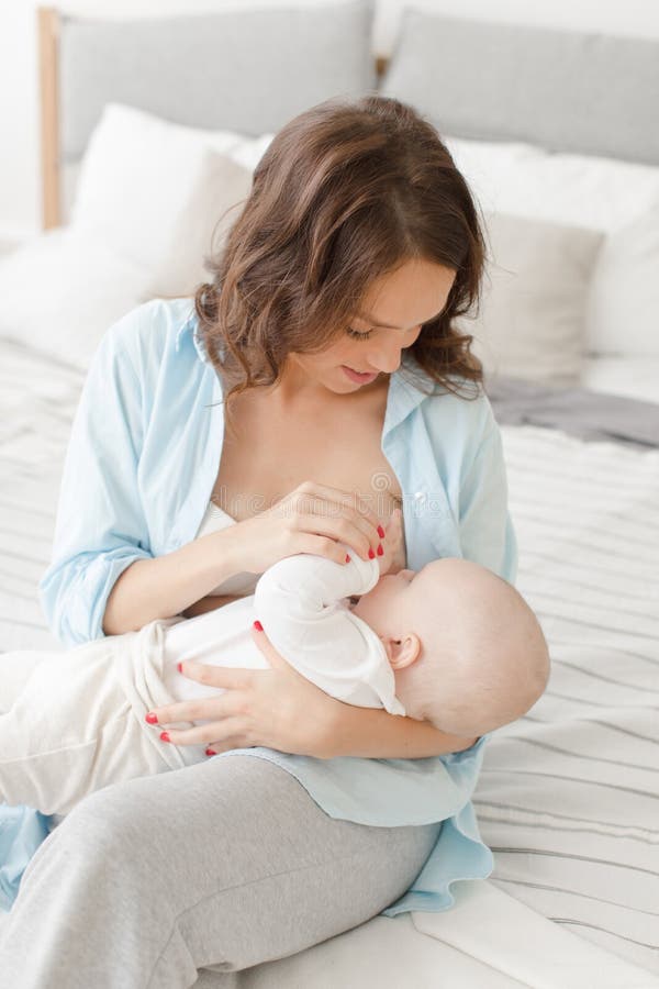 Cheerful woman with baby breast feeding