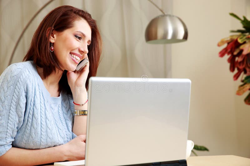 Cheerful woman talking on the phone at her workplace stock photography