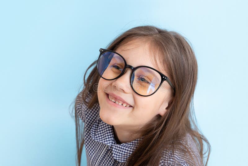 Cheerful 7-year-old girl in glasses with a smile on blue background. Children\ s education, learning concept