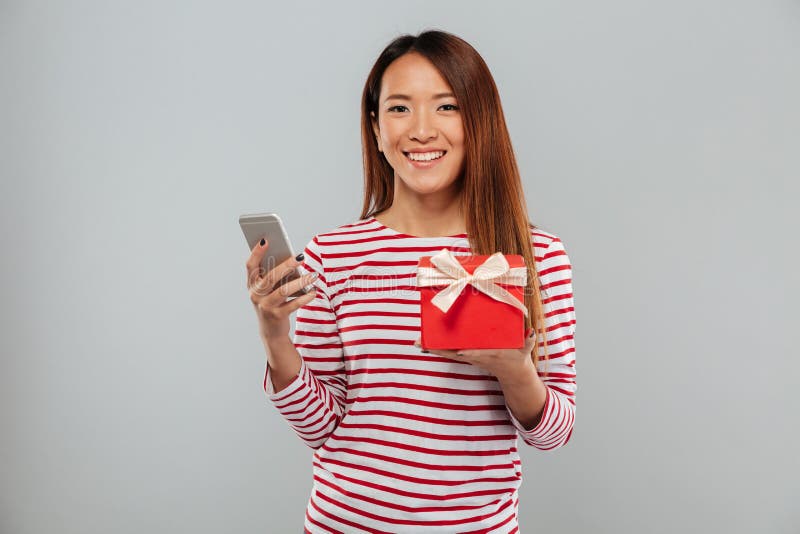 cheerful-young-asian-woman-chatting-phone-holding-gift-image-cheerful-young-asian-woman-chatting-phone-standing-isolated-103549561.jpg