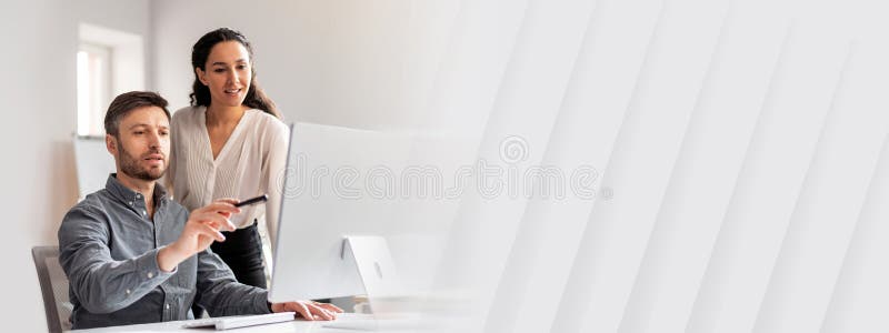 Cheerful young caucasian manager show to lady with hand at computer in modern office interior royalty free stock photography