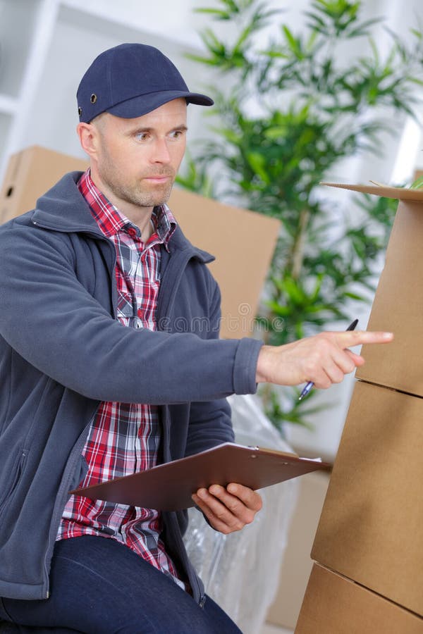 Cheerful young man mover holding cardboard boxes royalty free stock photos
