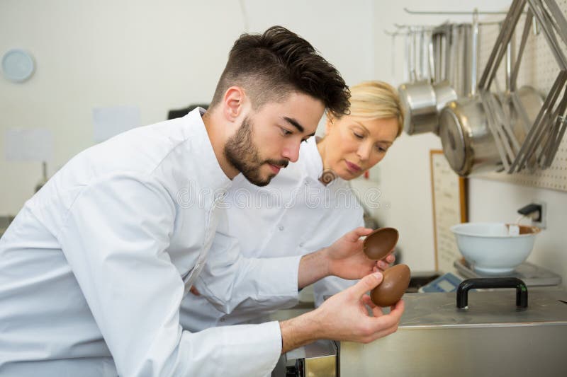 Cheerful young man professional pastry cook at work stock images