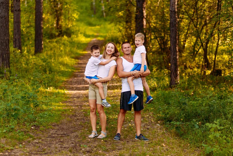 Cheerful young man and woman holding two children in the summer outdoors. family stock image Cheerful young man and woman holding two children in the summer outdoors. family stock image