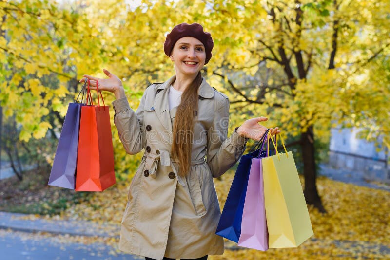 Cheerful young woman with shopping bags on autumn Park background. Fall discounts