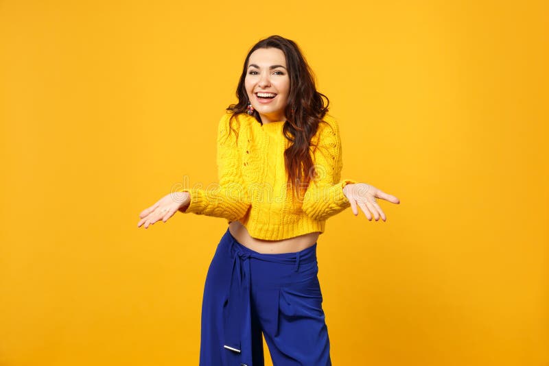 Cheerful Young Woman in Sweater, Blue Trousers Looking Camera Spreading ...