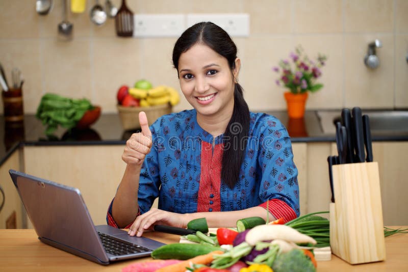 Cheerful young woman using a laptop in her kitchen