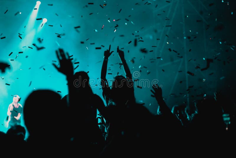 Cheering Crowd with Raised Hands and Falling Confetti at Concert ...