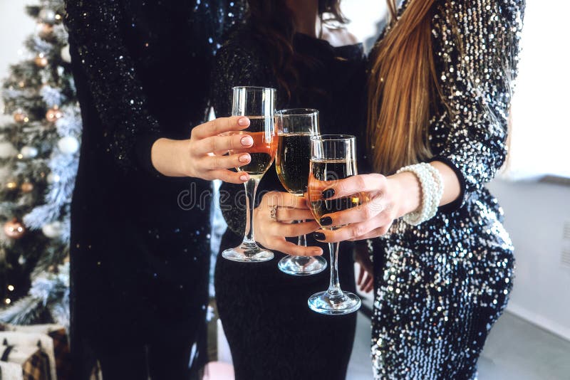 Cheers 2020! Close-up of female hand with glasses Champagne. Group of people cheering with champagne flutes in home, club. New