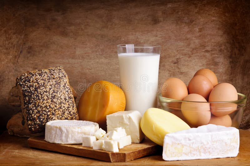 Ancora vita con latticini, latte, uova, pane e formaggio in legno vintage di sfondo.