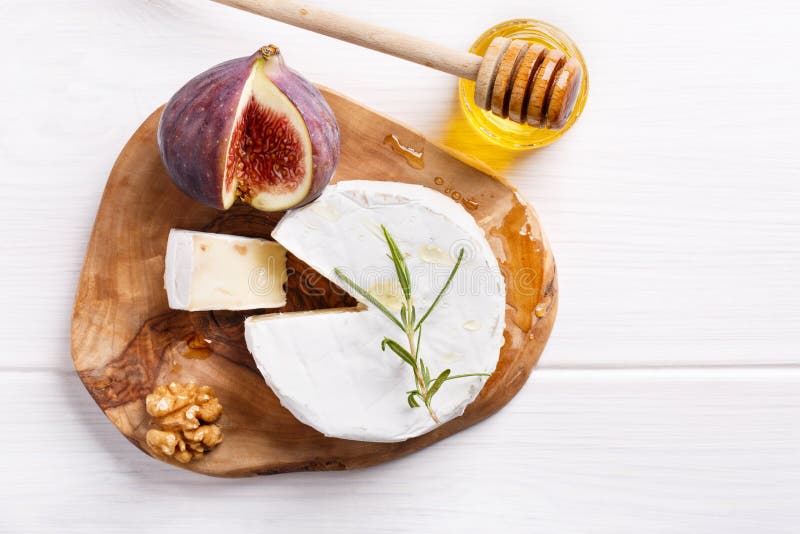 Cheese plate with brie, figs, honey and nuts on white table