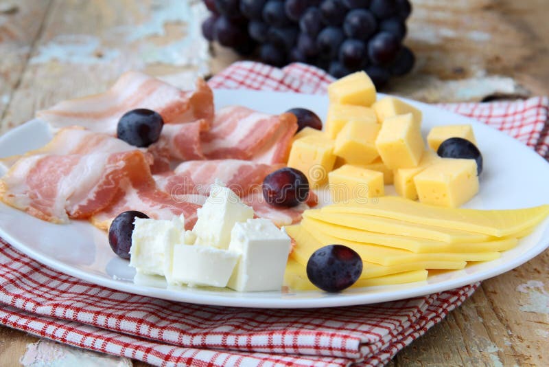 Cheese plate with grapes and smoked bacon