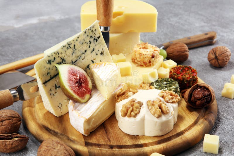 Cheese plate served with figs, various cheese on a platter on wood