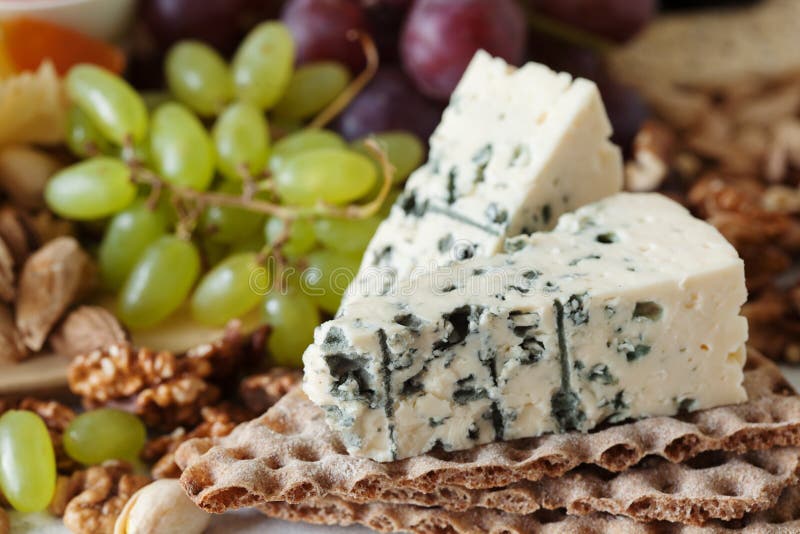 Cheese plate served with grapes, jam, cured melon, crackers and