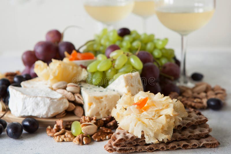 Cheese plate served with grapes, jam, cured melon, crackers and