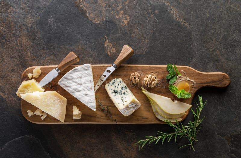 Cheese platter with different cheeses, wine and fruits on stone background. Top view