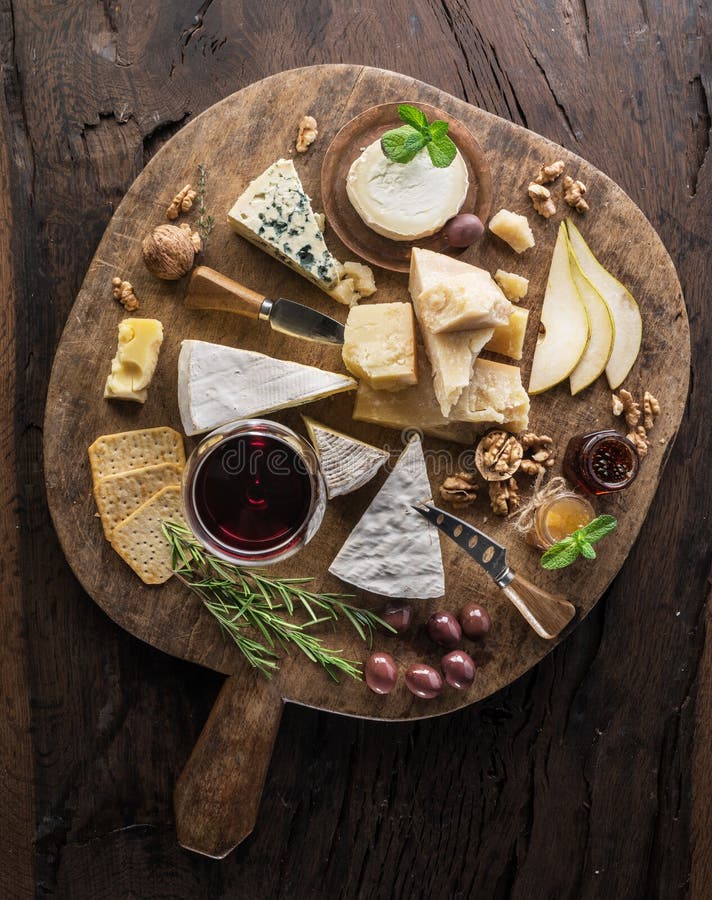 Cheese platter with organic cheeses, fruits, nuts and wine on wooden background. Top view. Tasty cheese starter royalty free stock photo