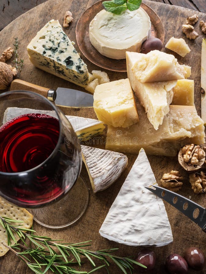 Cheese platter with organic cheeses, fruits, nuts and wine on wooden background. Top view. Tasty cheese starter stock photography