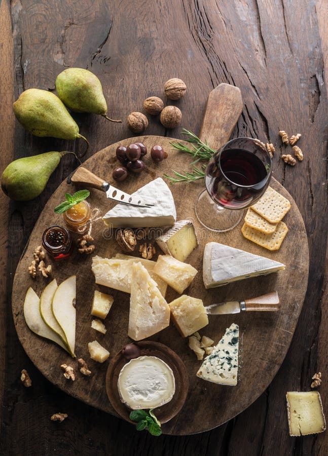 Cheese platter with organic cheeses, fruits, nuts and wine on wooden background. Top view. Tasty cheese starter royalty free stock images