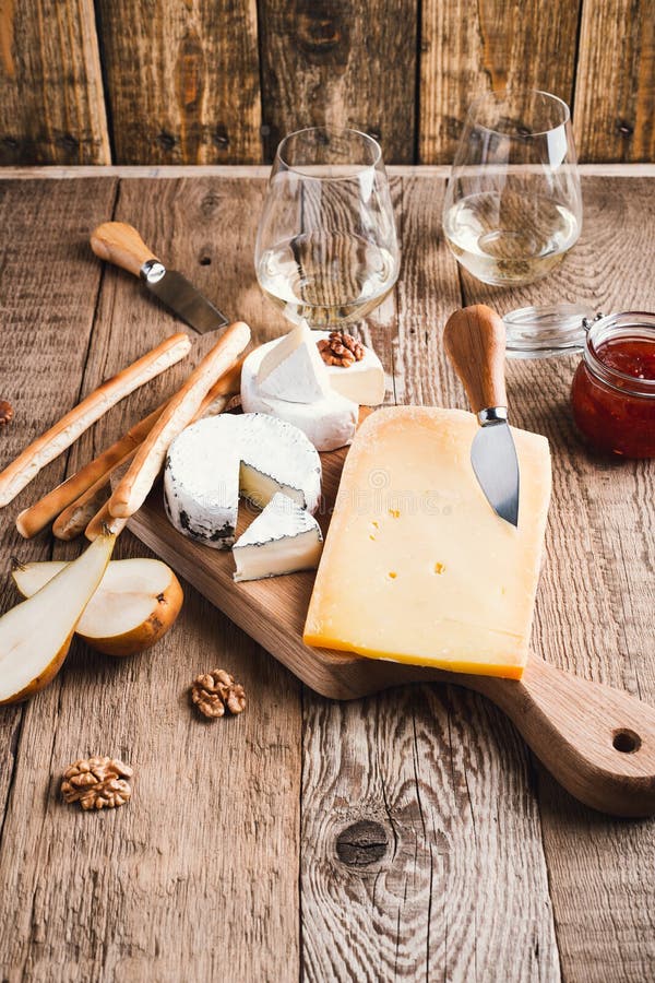 Cheese Platter with Wine, Jam and Walnuts on Wooden Board Stock Photo
