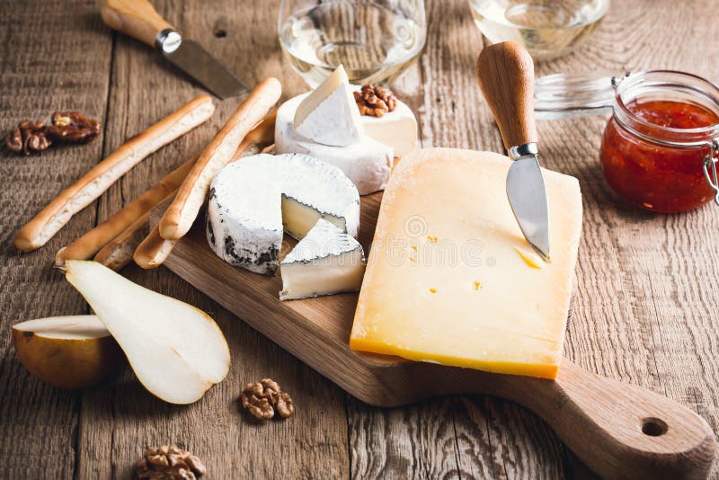 Cheese Platter with Wine, Jam and Walnuts on Wooden Board Stock Photo