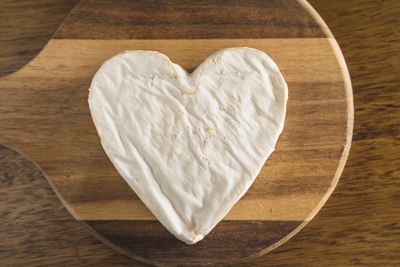 Cheese shape heart on the wooden cutting board. stock photography