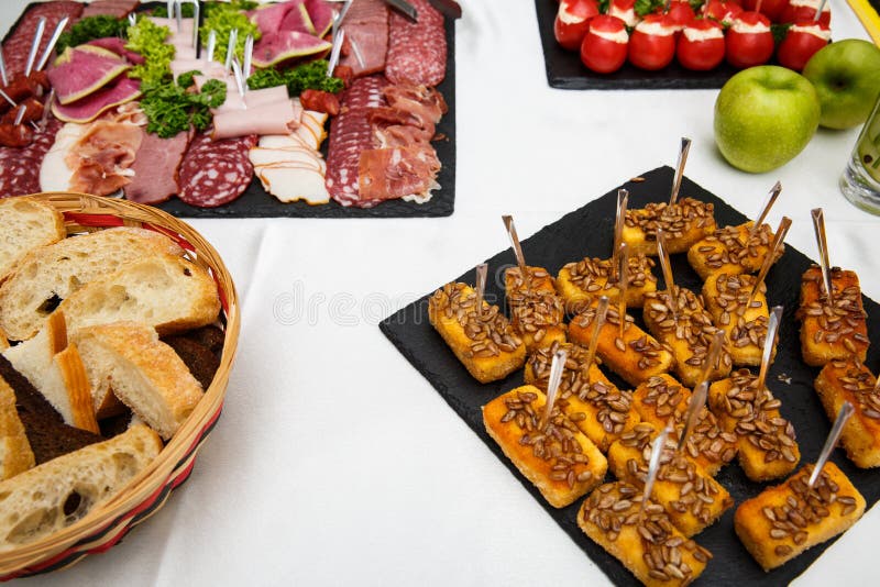 Cheese sticks. Food tray with delicious salami, pieces of sliced ham, sausage, salad. Bread. Tomatoes stuffed with cheese and garl stock image Cheese sticks. Food tray with delicious salami, pieces of sliced ham, sausage, salad. Bread. Tomatoes stuffed with cheese and garl stock image