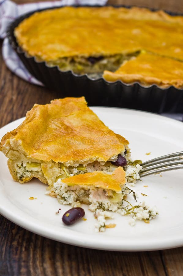 Cheese tart with leek and red beans. Salty tart with feta cheese, leek and red beans on a wooden board. Showing a separate slice on a plate royalty free stock photos Cheese tart with leek and red beans. Salty tart with feta cheese, leek and red beans on a wooden board. Showing a separate slice on a plate royalty free stock photos