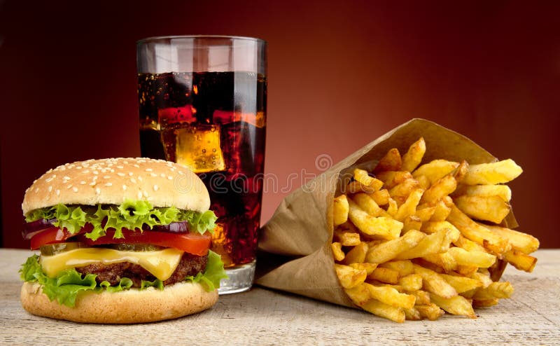 Cheeseburger met drank van kola en frieten op rode schijnwerper stock foto's Cheeseburger met drank van kola en frieten op rode schijnwerper stock foto's