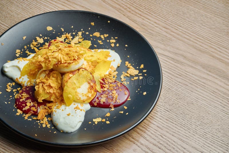 cheesecake fatti in casa o Syrniki con marmellata, zucca e panna acida su un piatto nero su fondo di legno Cibo ucraino fotografia stock cheesecake fatti in casa o Syrniki con marmellata, zucca e panna acida su un piatto nero su fondo di legno Cibo ucraino fotografia stock