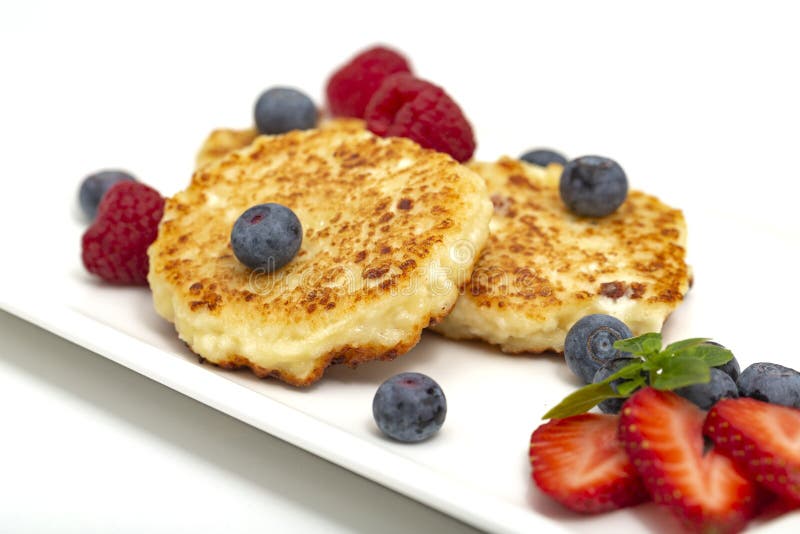 Cheesecakes from cottage cheese with raspberries, strawberries and blueberries. stock photo Cheesecakes from cottage cheese with raspberries, strawberries and blueberries. stock photo