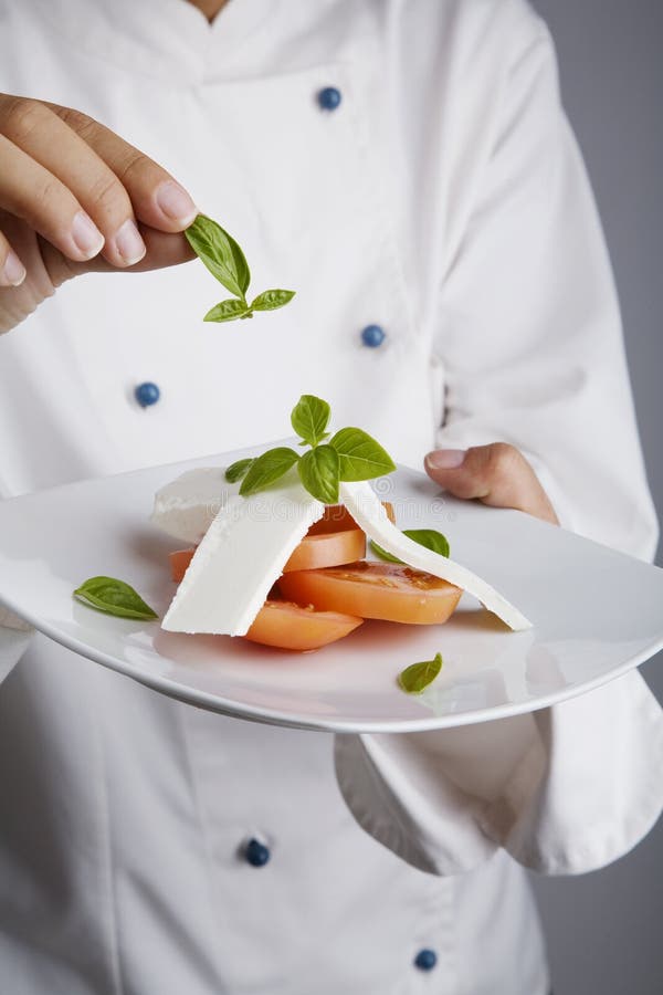 Chef adding greens to dish stock images