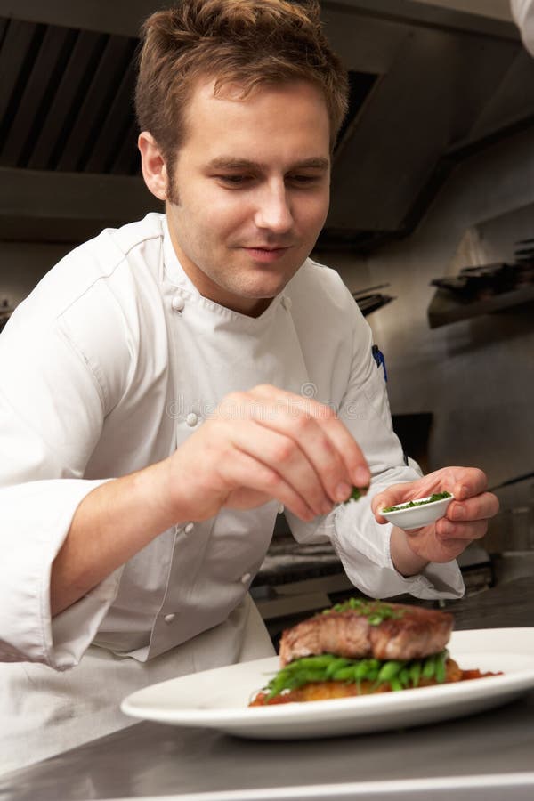 Chef Adding Seasoning To Dish In Restaurant stock photography Chef Adding Seasoning To Dish In Restaurant stock photography