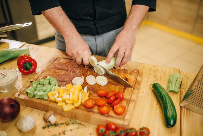 Chef avec des champignons de coupes de couteau sur le conseil en bois photographie stock libre de droits Chef avec des champignons de coupes de couteau sur le conseil en bois photographie stock libre de droits