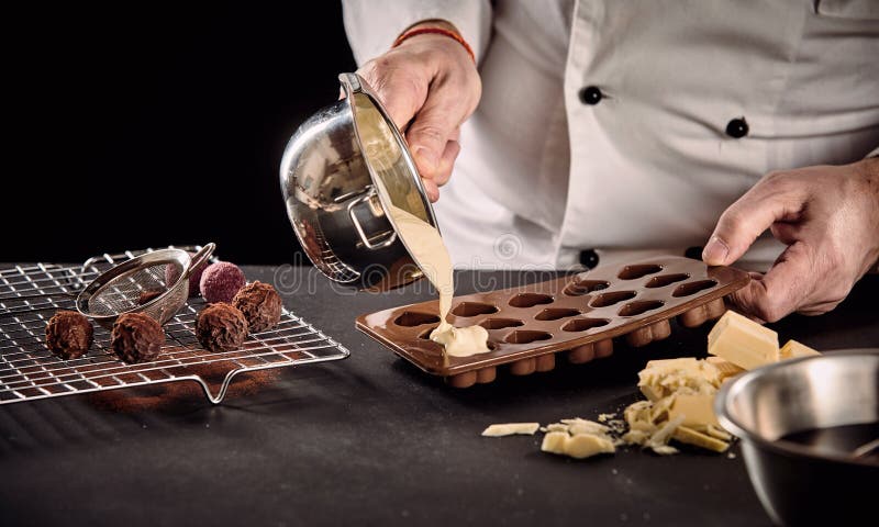 Šéfkuchár alebo odlievanie tavený biely čokoláda silikón formy panvica v z blízka na jeho ruky.