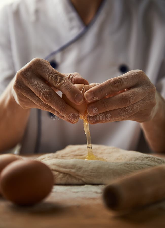 Woman hands breaking egg on pasta dough. Fresh ingredients. Meal preparation. Woman hands breaking egg on pasta dough. Fresh ingredients. Meal preparation.