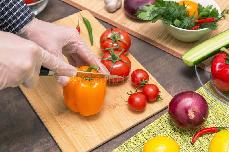 Chef cooking healthy vegetarian vegan diet food. Hands in latex gloves cutting orange pepper and different vegetables. Chef cooking healthy vegetarian vegan diet food. Hands in latex gloves cutting orange pepper and different vegetables