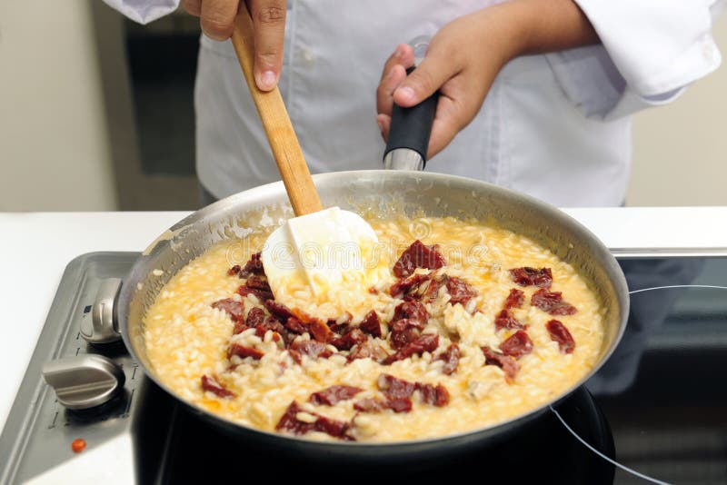 Chef cooking risotto with dried tomato