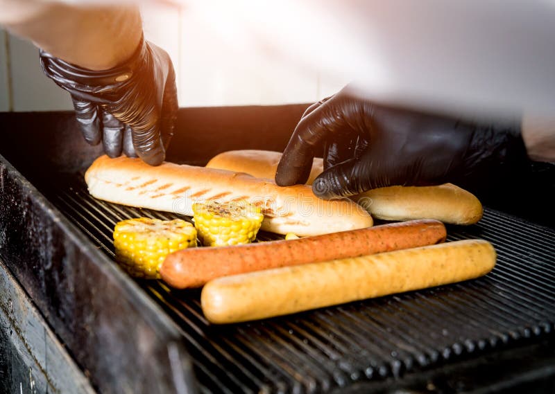 The Chef Cooking Two Hot Dogs on a Grill. Restaurant. Stock Photo