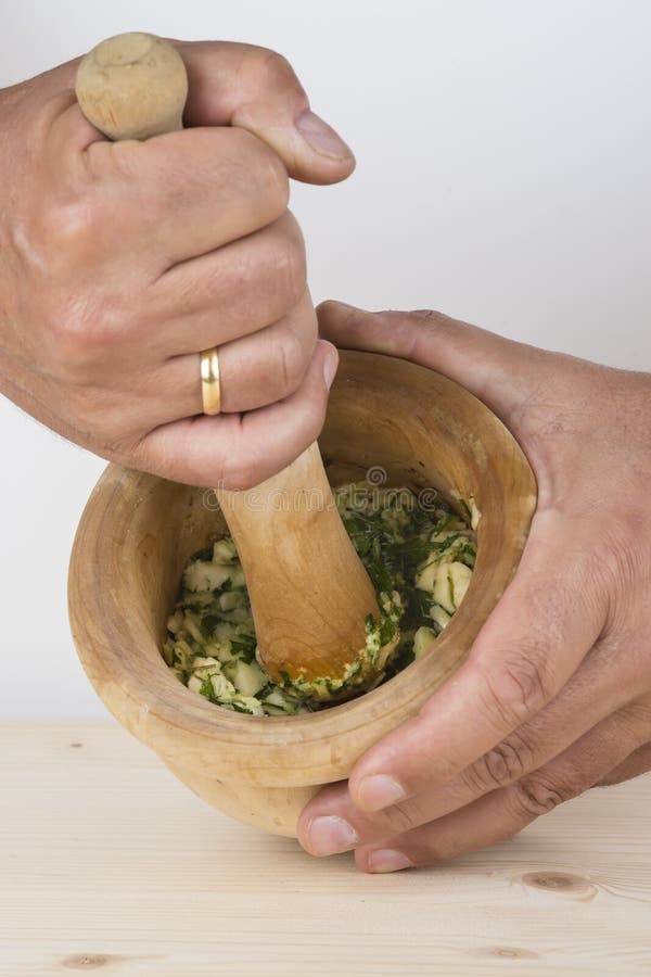 Chef crushing garlic and parsley with mortar and pestle in the k