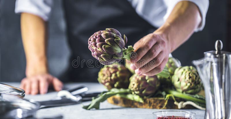 Chef cutting artichokes for dinner preparation - Man cooking inside restaurant kitchen royalty free stock image Chef cutting artichokes for dinner preparation - Man cooking inside restaurant kitchen royalty free stock image