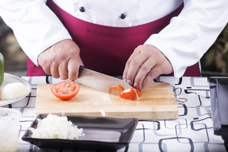 Chef cutting Tomato with knife before cooking. Cook, restaurant.