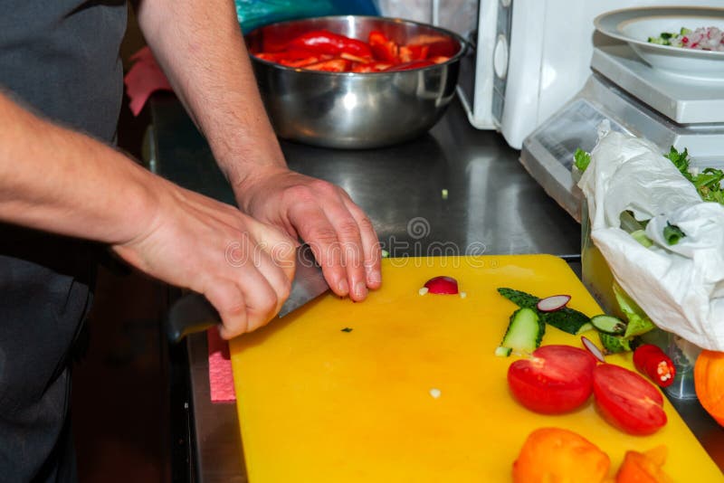 Chef is Cutting Vegetables on a Plastic Yellow Cutting Board Stock