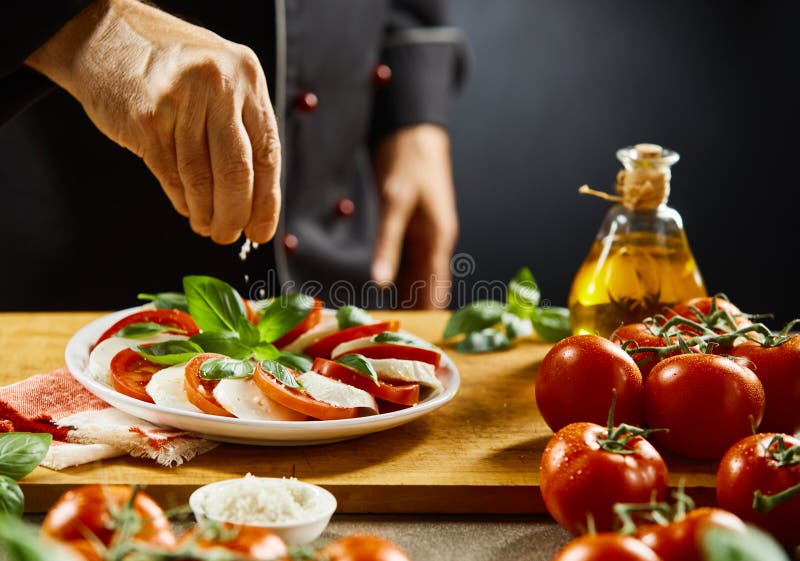Chef, der einen Caprese-Salat mit Salz würzt stockbilder