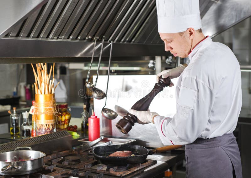Chef in der Restaurantküche am Ofen mit der Wanne, kochend lizenzfreie stockfotos Chef in der Restaurantküche am Ofen mit der Wanne, kochend lizenzfreie stockfotos