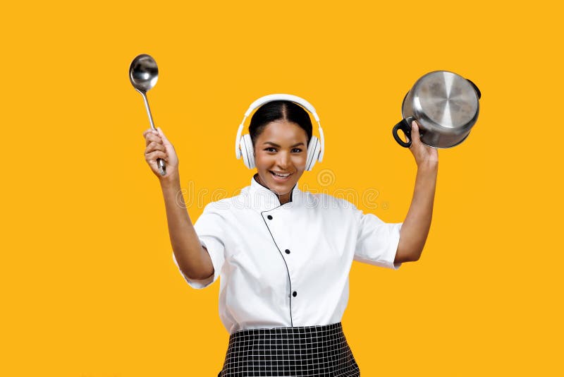 Happy black female chef enjoying music in headphones while holding ladle and pot, cheerful young african american cook woman having fun against bright yellow background, merging cooking with joy. Happy black female chef enjoying music in headphones while holding ladle and pot, cheerful young african american cook woman having fun against bright yellow background, merging cooking with joy