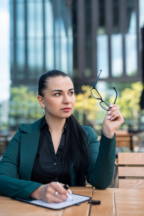 Chef einer Geschäftsfrau mit einem dunklen Business-Anzug, der eine Tablette im Freien hält stockbild