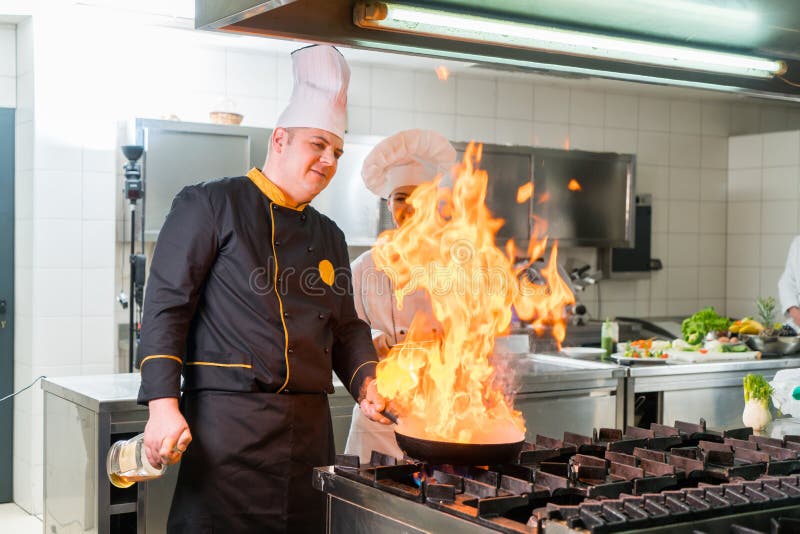 Chef expert préparant le repas tandis que donner son assistant incline photos stock Chef expert préparant le repas tandis que donner son assistant incline photos stock