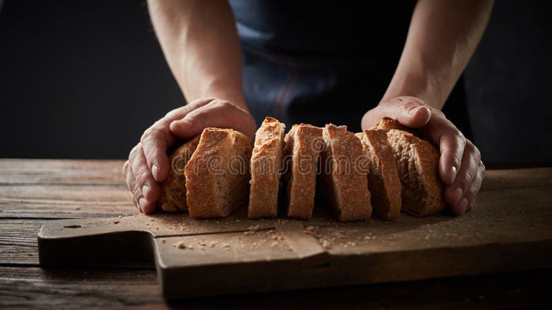 Chef holding a bread in front of a wooden cutting board royalty free stock photo Chef holding a bread in front of a wooden cutting board royalty free stock photo